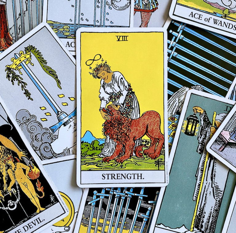 Strength Card on top of pile of Rider Waite Smith tarot cards